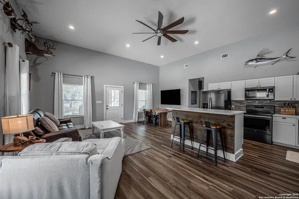 a living room with stainless steel appliances furniture and a flat screen tv