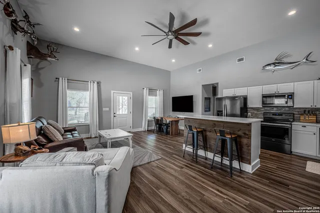 a living room with stainless steel appliances furniture and a flat screen tv