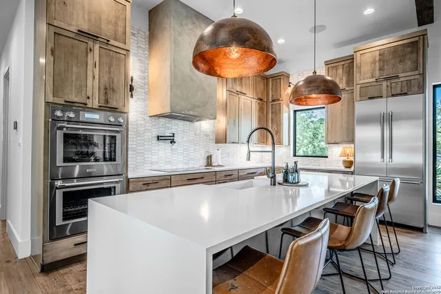 a kitchen with stainless steel appliances a table chairs and a refrigerator