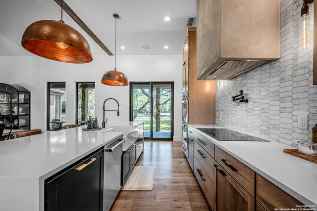 a kitchen with stainless steel appliances granite countertop a sink a stove and a wooden floors