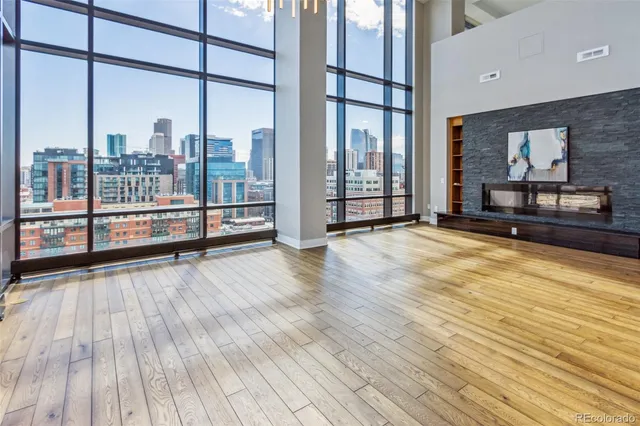 a view of an empty room and kitchen with wooden floor