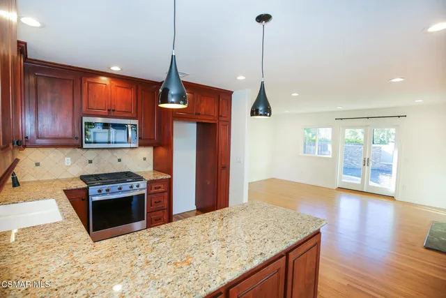 a kitchen with stainless steel appliances granite countertop a refrigerator a sink and a stove