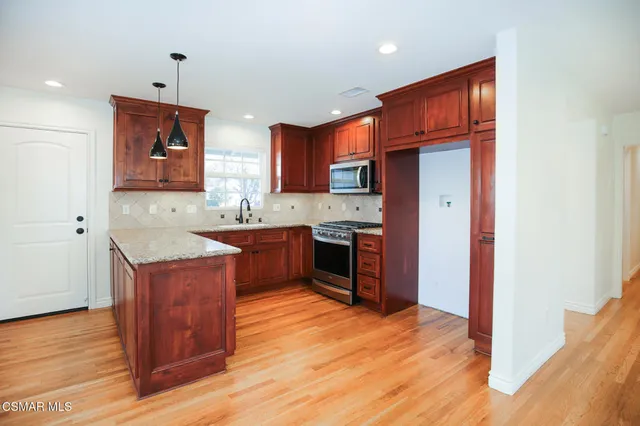 a kitchen with stainless steel appliances granite countertop a stove a sink and a refrigerator
