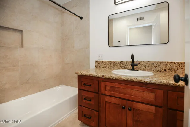a bathroom with a granite countertop sink a mirror and a bathtub