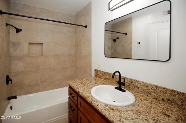 a bathroom with a granite countertop sink a mirror and shower