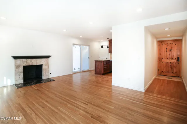 a view of empty room with wooden floor and fireplace