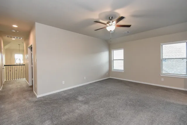 an empty room with fan and windows