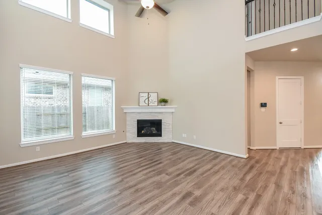 an empty room with wooden floor fireplace and windows