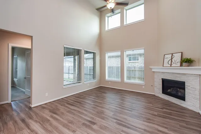 a view of an empty room with wooden floor fireplace and a window
