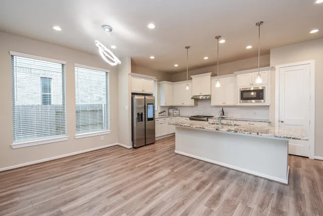 a large kitchen with stainless steel appliances kitchen island a large counter top and a wooden floors