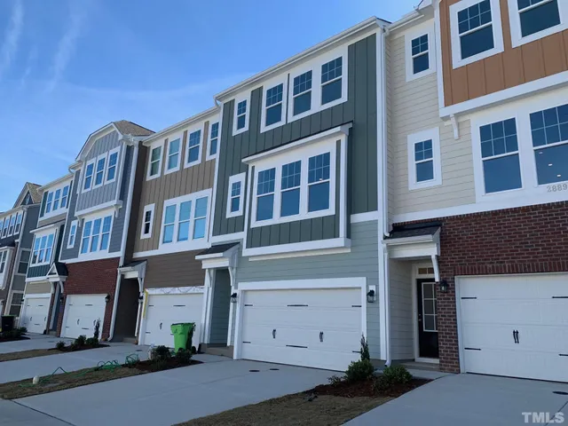 a front view of a building with a garden and parking space