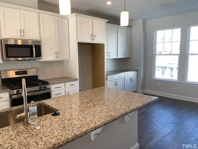 a kitchen with stainless steel appliances granite countertop a stove a sink and a microwave