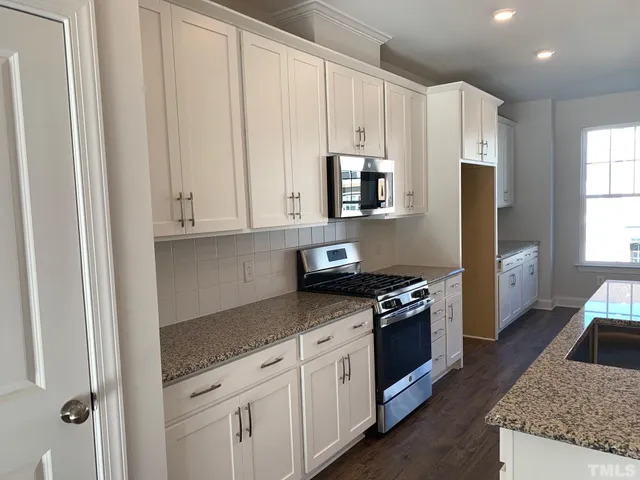 a kitchen with stainless steel appliances granite countertop a stove a sink and a refrigerator