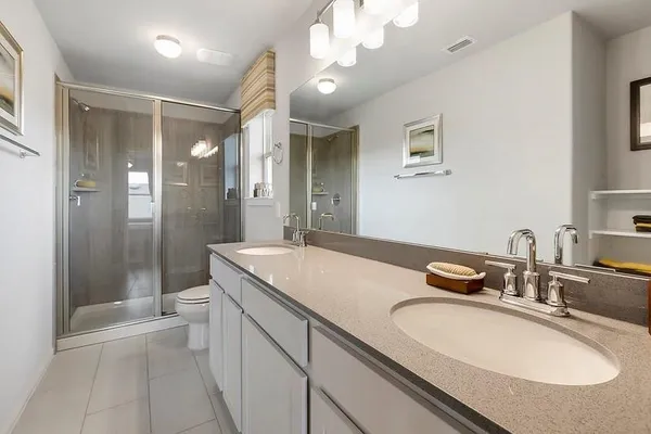 a bathroom with a granite countertop sink a toilet a mirror and shower
