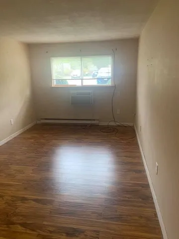 a view of an empty room with wooden floor and window