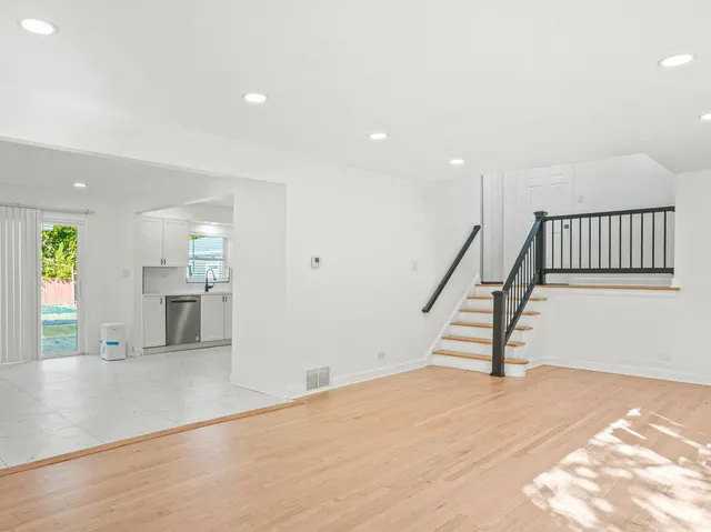 a view of a hallway with wooden floor and a kitchen
