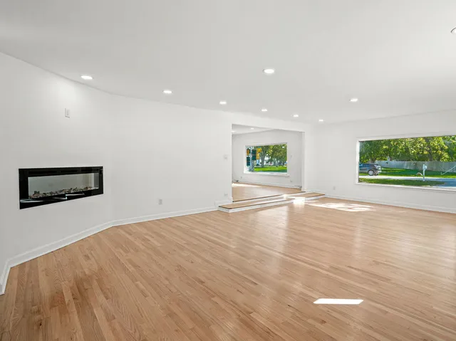 a view of empty room with wooden floor and window