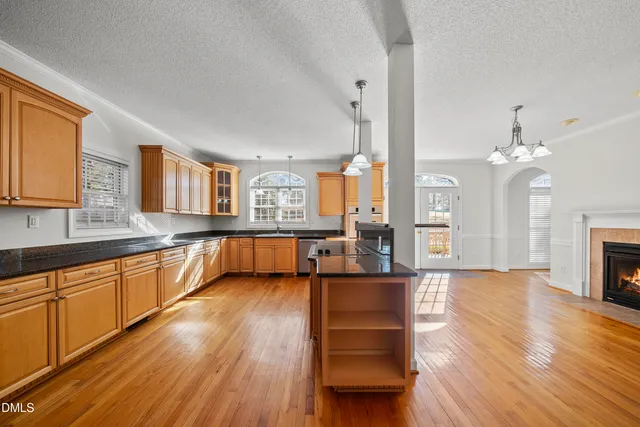 a large living room with stainless steel appliances granite countertop couches a fireplace and a large window with wooden floor