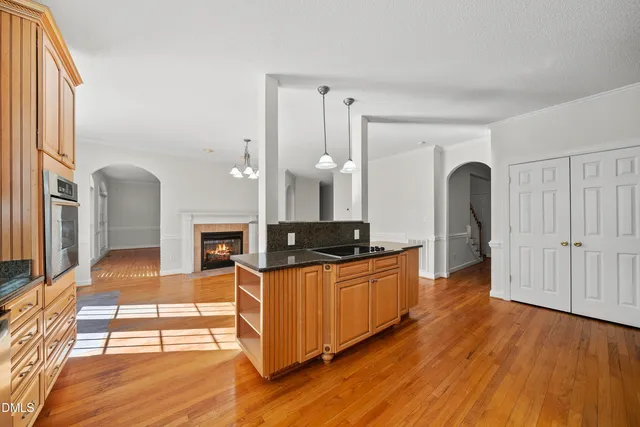 a large living room with stainless steel appliances kitchen island granite countertop a refrigerator a stove a sink and dishwasher with wooden floor