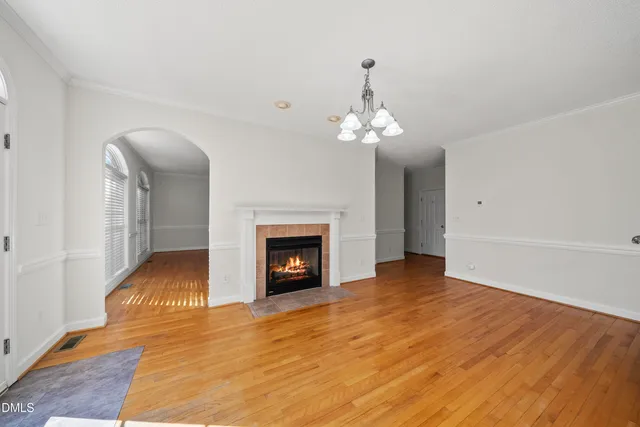 a view of an empty room with wooden floor and fireplace
