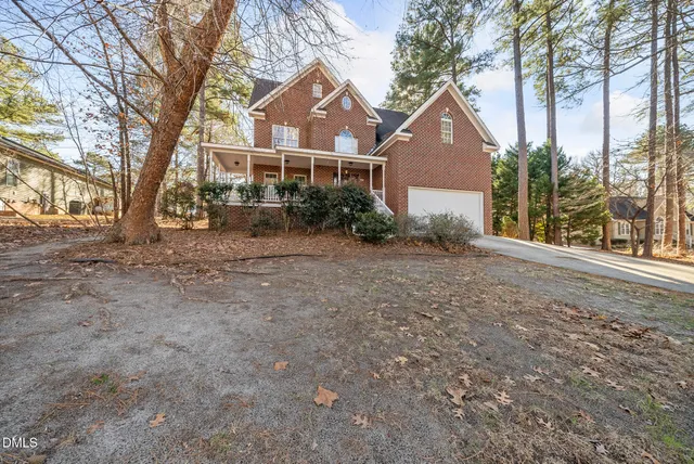 a front view of a house with a yard and large tree
