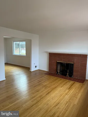an empty room with wooden floor fireplace and windows