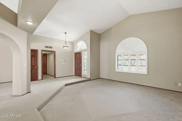a view of a livingroom with a chandelier fan and windows