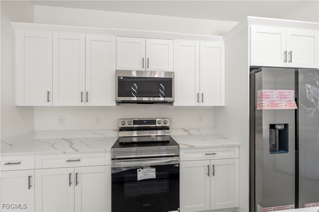 4649-4651 24th Street Southwest Lehigh Acres, FL 33973 - Photo 18 of 29 a kitchen with stainless steel appliances granite countertop white cabinets and a stove