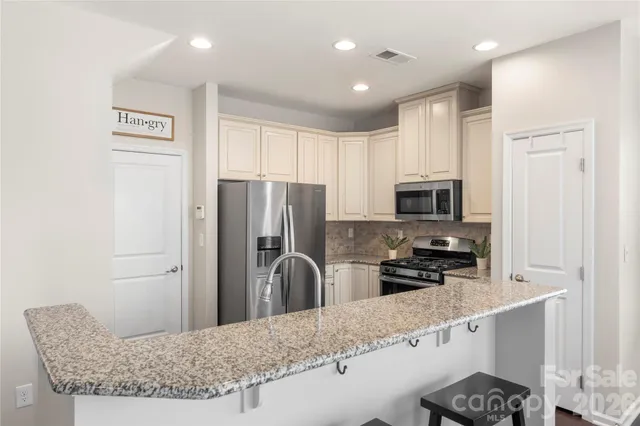 a kitchen with stainless steel appliances granite countertop a refrigerator and a stove top oven