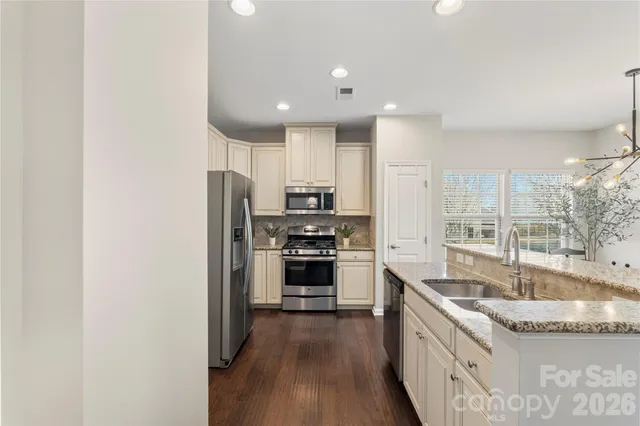 a kitchen with stainless steel appliances granite countertop a sink stove and refrigerator