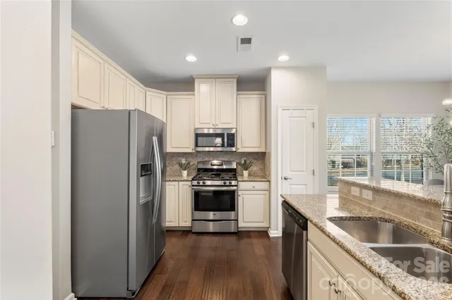 a kitchen with stainless steel appliances granite countertop a refrigerator stove and sink