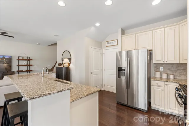 a kitchen with granite countertop a refrigerator and a stove top oven