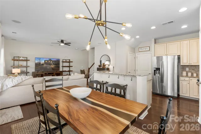 a kitchen with stainless steel appliances kitchen island granite countertop a refrigerator a stove a sink dishwasher a dining table and chairs with wooden floor