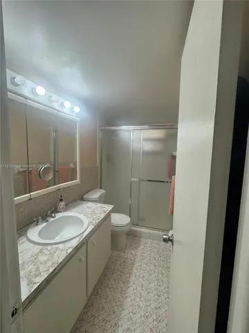 a bathroom with a granite countertop sink a toilet and shower