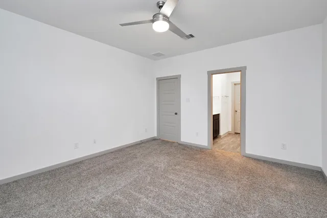 an empty room with closet and a ceiling fan