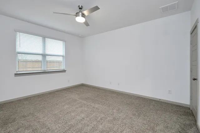 an empty room with a window and ceiling fan