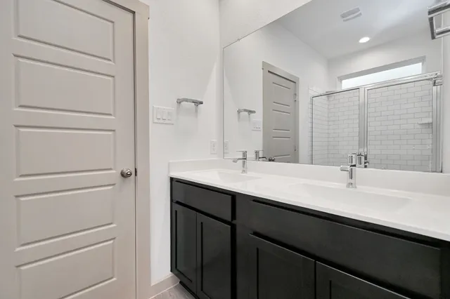 a bathroom with a double vanity sink a mirror and a bathtub