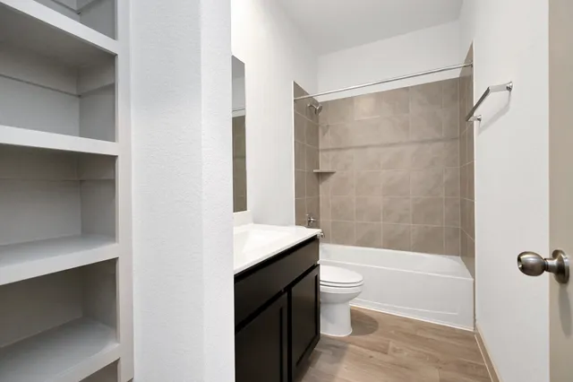 a bathroom with a granite countertop bathtub shower sink vanity and toilet