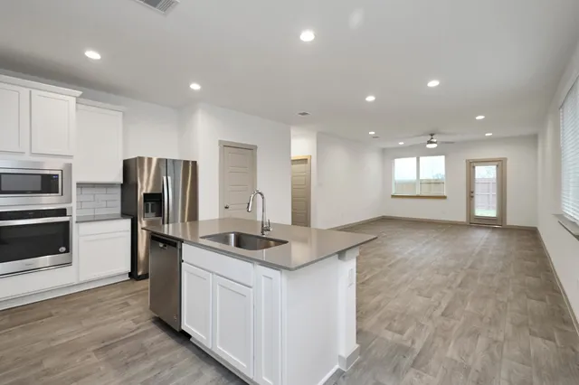 a kitchen with stainless steel appliances granite countertop a sink a stove and a refrigerator