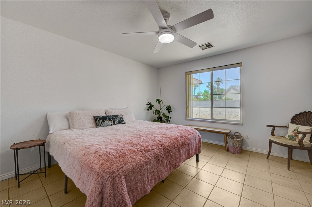1272 Liston Avenue Logandale, NV 89021 - Photo 34 of 61 A well-lit sleeping sanctuary features a window overlooking palm trees and durable tile flooring.