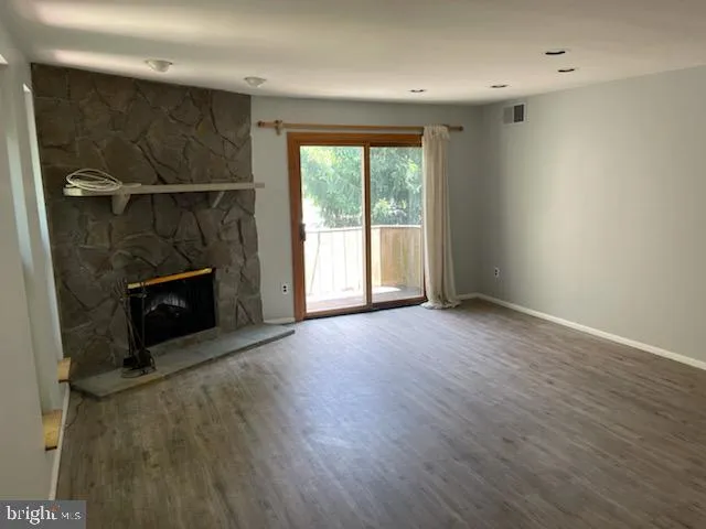 an empty room with wooden floor and a fireplace
