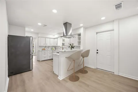 a kitchen with kitchen island white cabinets and stainless steel appliances