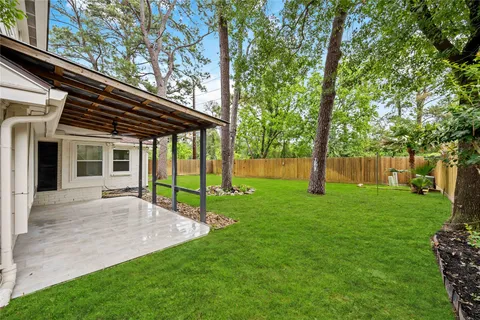 a house that is sitting in the grass with tress in the background