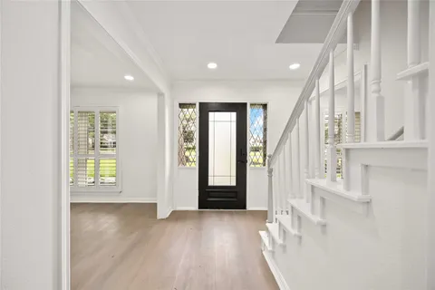an entryway in a hall with wooden floor and a window