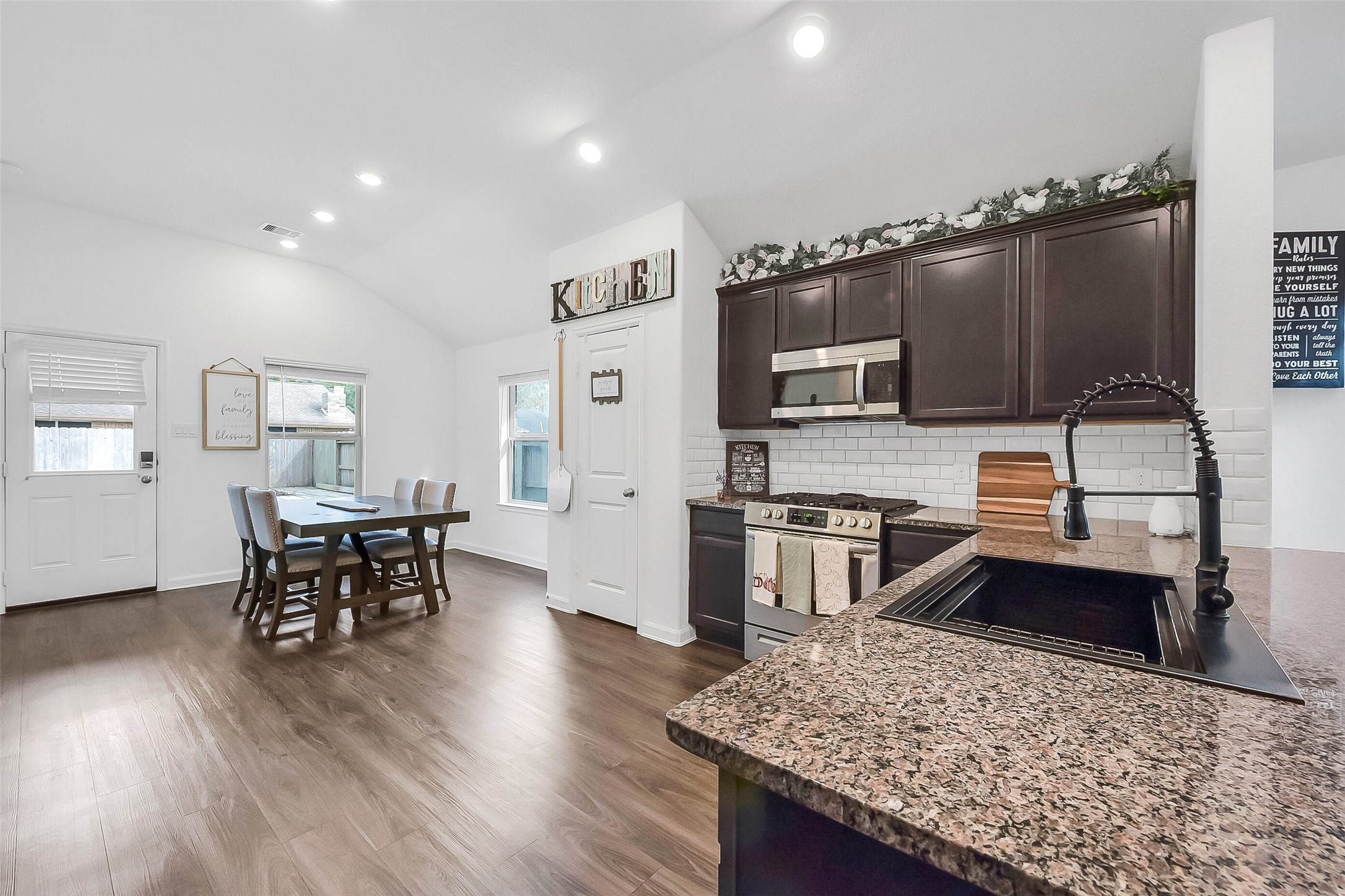 1004 Bulwark Crosby, TX 77532 - Photo 12 of 29 a kitchen with stainless steel appliances granite countertop a stove top oven a sink dishwasher a dining table and chairs with wooden floor