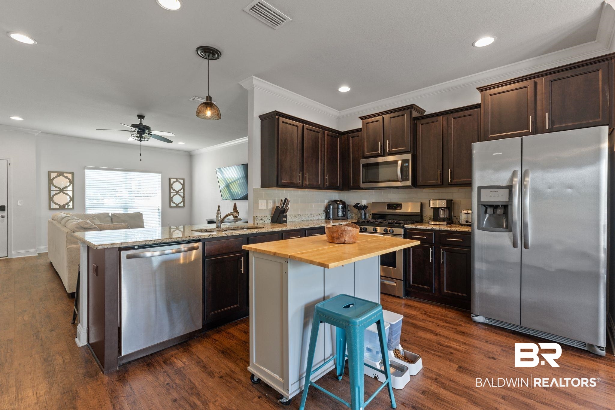 12711 Chickadee Lane Daphne, AL 36527 - Photo 39 of 39 Kitchen featuring dark brown cabinetry, appliances with stainless steel finishes, open floor plan, decorative backsplash, and ornamental molding