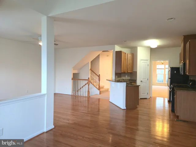 a view of a living room with kitchen view and wooden floor