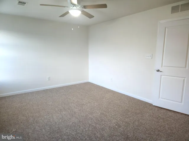 an empty room with a ceiling fan and window