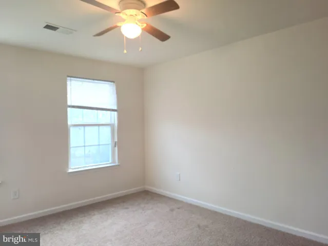 an empty room with a window and a fan