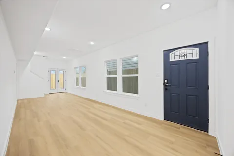 a view of an empty room with a window and wooden floor